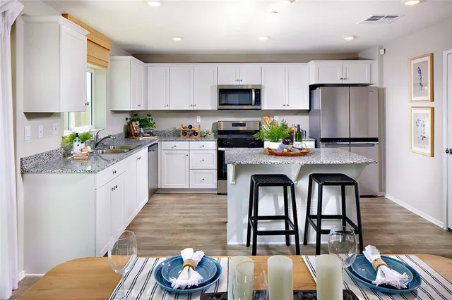 a kitchen with stainless steel appliances a dining table a stove a microwave and cabinets