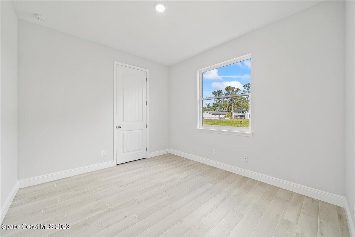 560 Topeka Road Southwest Palm Bay, FL 32908 - Photo 13 of 26 an empty room with wooden floor and windows