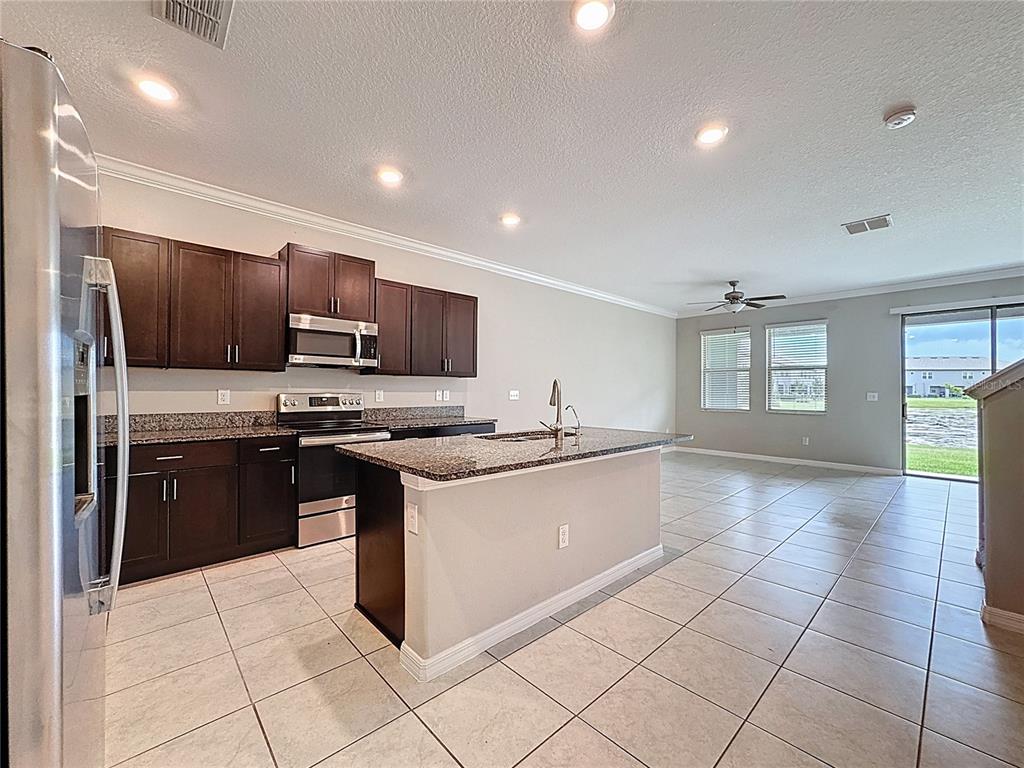 8069 Rolling Shell Trail Wesley Chapel, FL 33545 - Photo 4 of 26 a large kitchen with a large counter top stainless steel appliances and cabinets