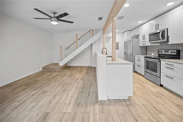 a living room with stainless steel appliances kitchen island hardwood floor and a view of living room