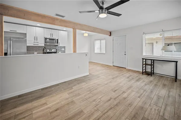 a living room with stainless steel appliances kitchen island hardwood floor and a sink