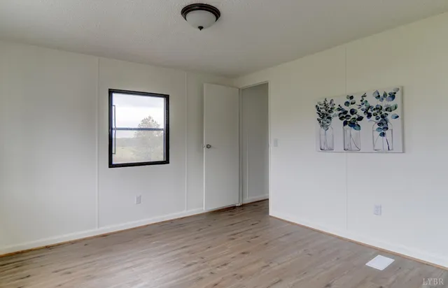 an empty room with wooden floor cabinet and windows