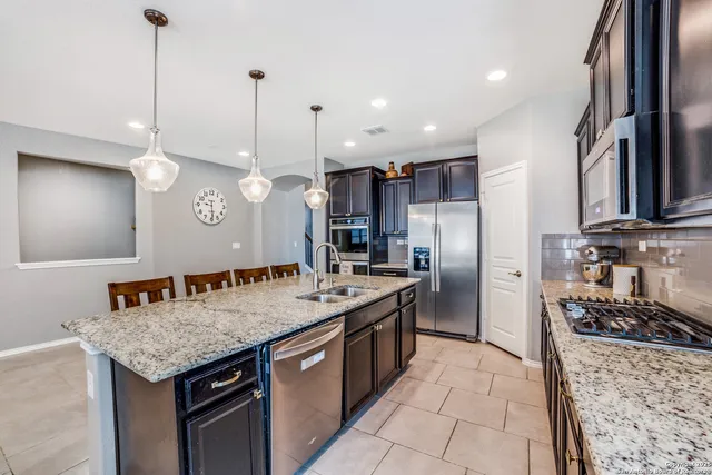 a kitchen with stainless steel appliances granite countertop a sink a stove and a refrigerator