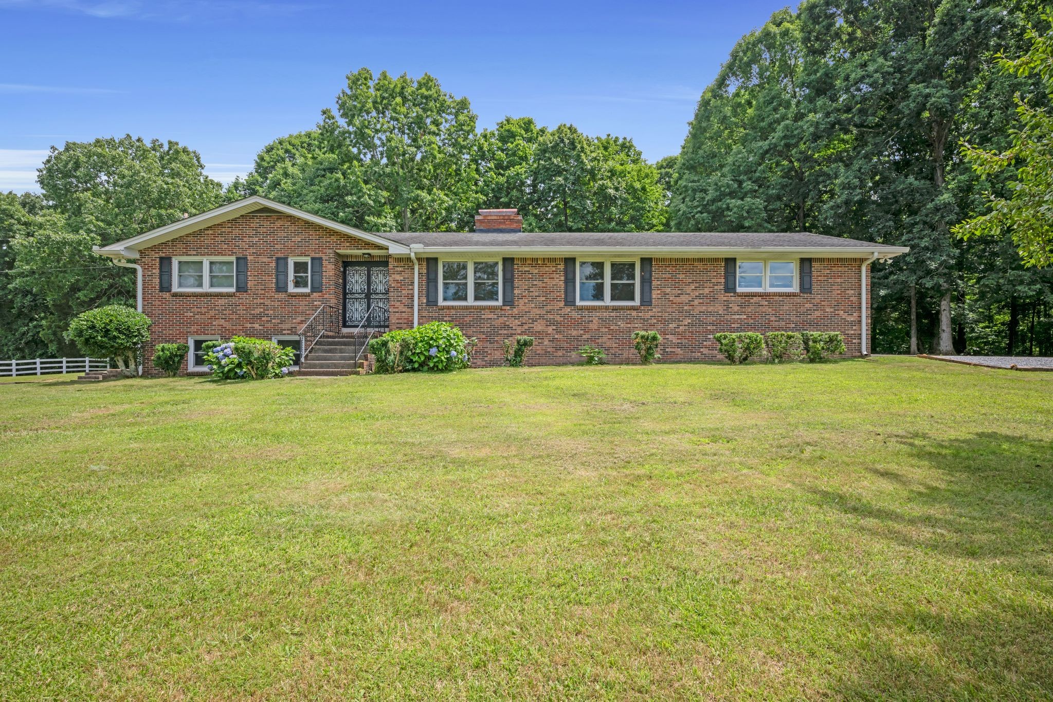 1300 2 Mile Road Burns, TN 37029 - Photo 1 of 38 a house that is sitting in the grass with large trees and plants