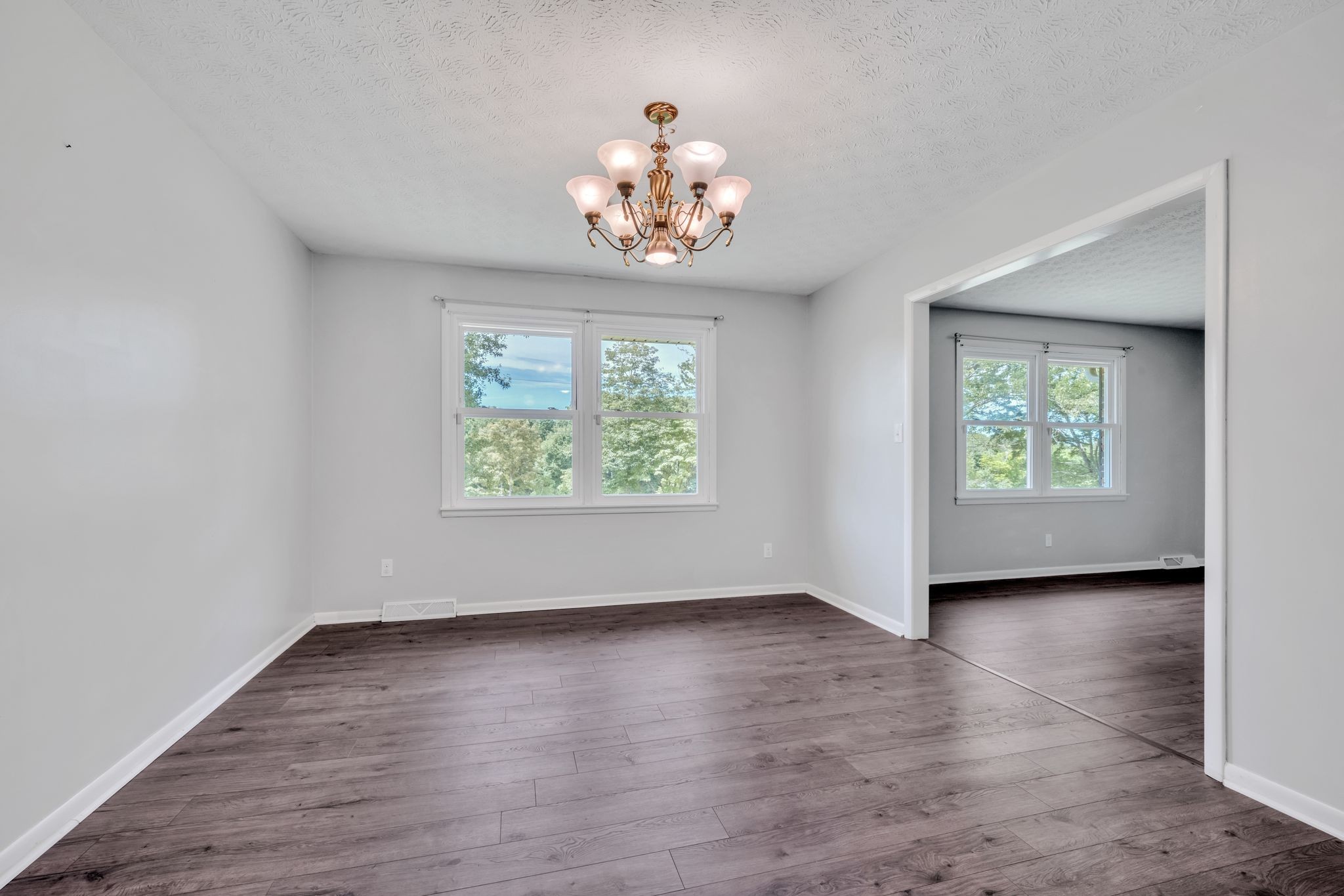 1300 2 Mile Road Burns, TN 37029 - Photo 13 of 38 an empty room with wooden floor chandelier and windows