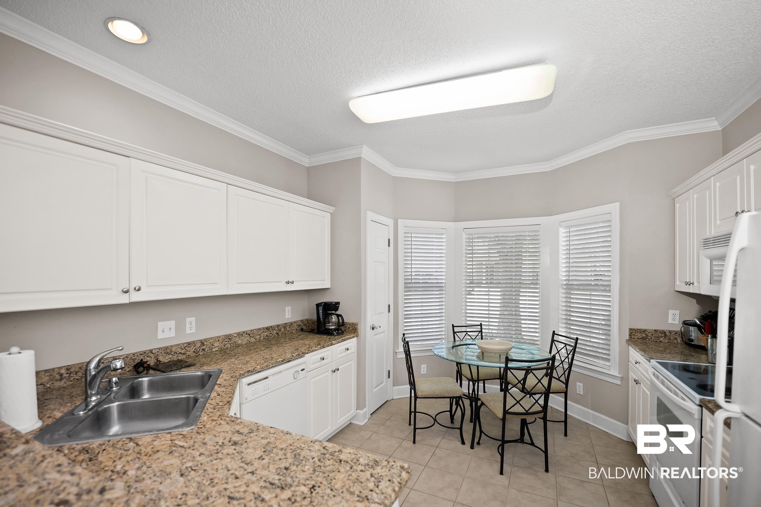 430 West Fort Morgan Road, Unit 704 Gulf Shores, AL 36542 - Photo 7 of 35 Kitchen featuring white cabinetry, granite-finish countertops, and a double basin stainless steel sink