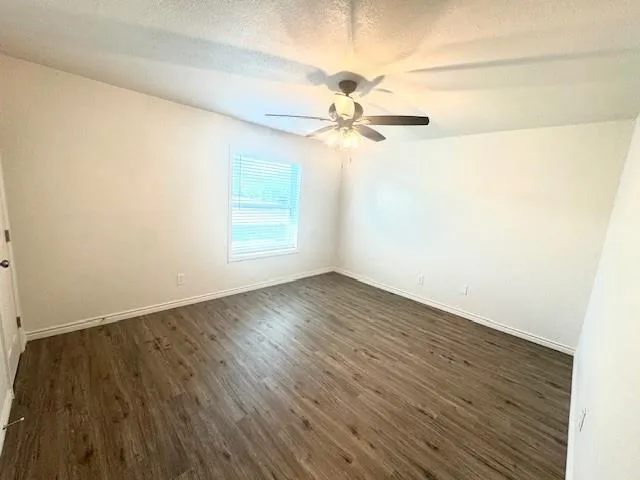 an empty room with wooden floor fan and windows
