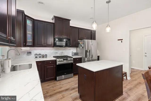 a kitchen with stainless steel appliances granite countertop a refrigerator a sink dishwasher a stove with wooden cabinets