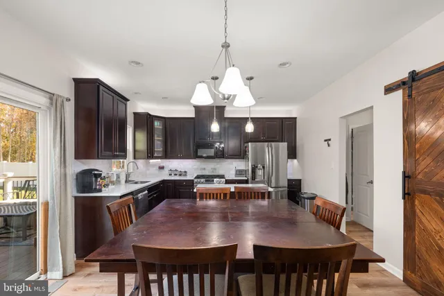 a dining room with wooden floor a chandelier a wooden table and chairs