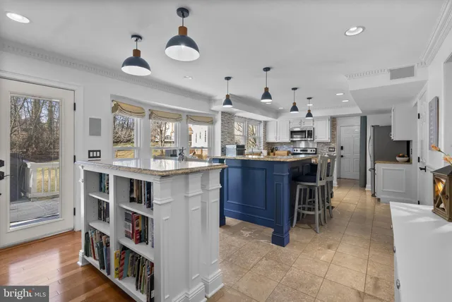 a kitchen with stainless steel appliances kitchen island granite countertop a stove a refrigerator a sink a dining table and chairs with wooden floor