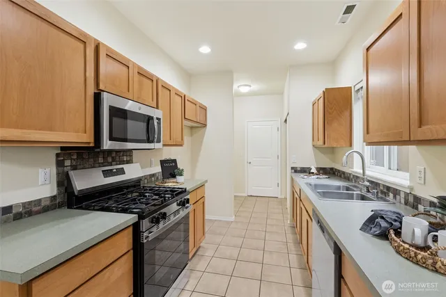 a kitchen with kitchen island granite countertop a sink stainless steel appliances and cabinets