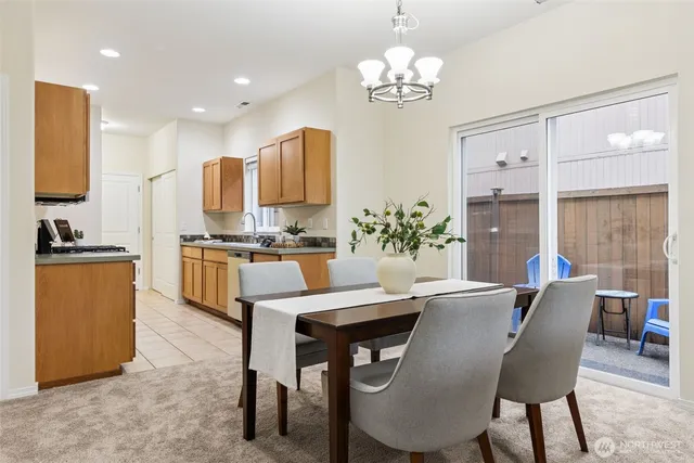 a kitchen with stainless steel appliances kitchen island granite countertop a dining table chairs and a refrigerator