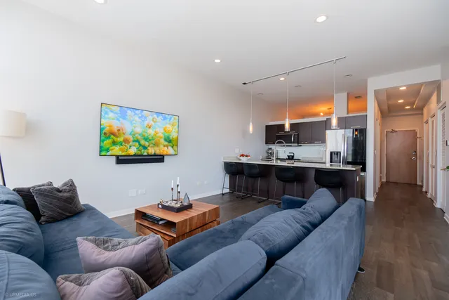 a living room with stainless steel appliances furniture and a kitchen view