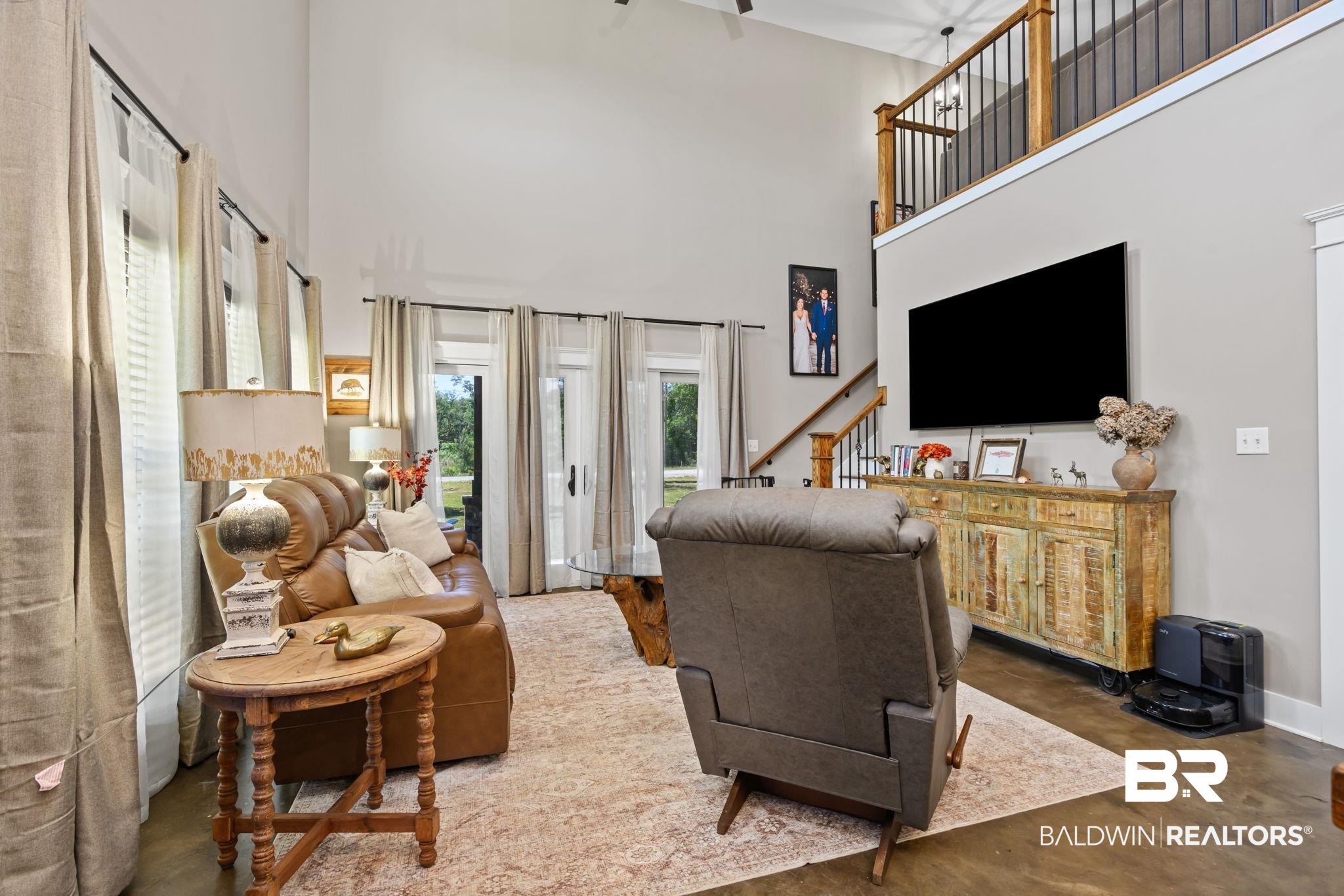 11025 Creax Road Axis, AL 36505 - Photo 11 of 45 Two-story living area featuring high ceilings, multiple French doors, a staircase with wood and iron railings, a wood-finish floor, and a second-story overlook