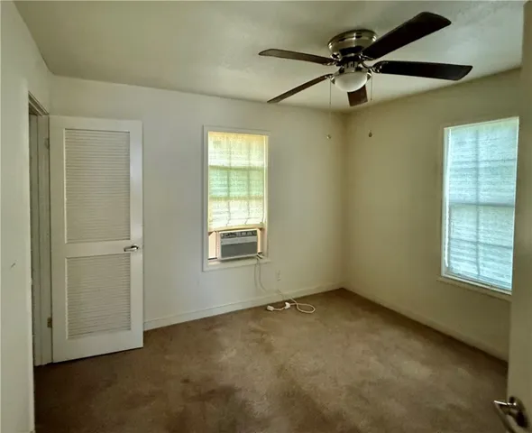 an empty room with a window and a fan