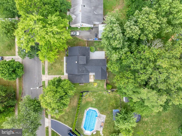 an aerial view of a house with outdoor space and trees all around
