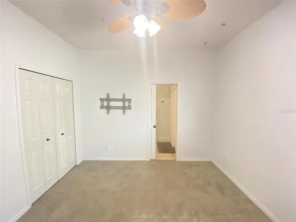 a view of an empty room with chandelier fan