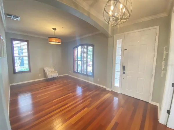a view of empty room with wooden floor and fan