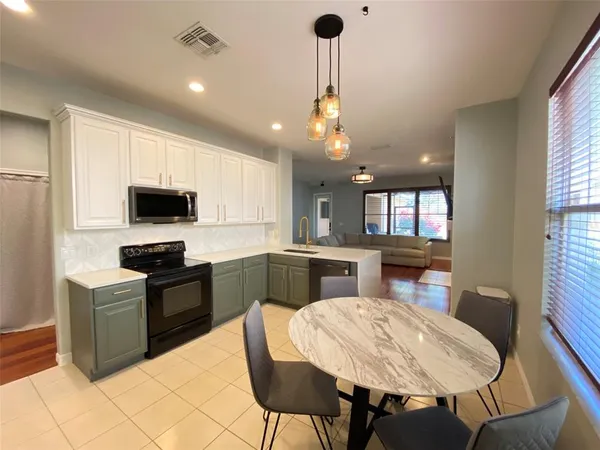 a kitchen with stainless steel appliances kitchen island granite countertop a sink a stove a microwave a dining table and chairs with wooden floor