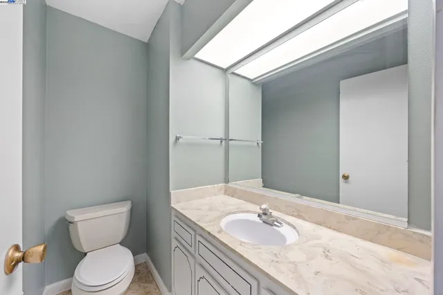 a bathroom with a granite countertop toilet sink and mirror