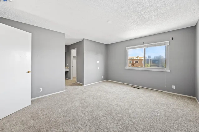 a view of an empty room with window and stairs
