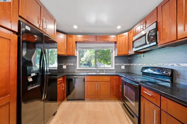 a kitchen with stainless steel appliances granite countertop a sink a stove and a wooden cabinets