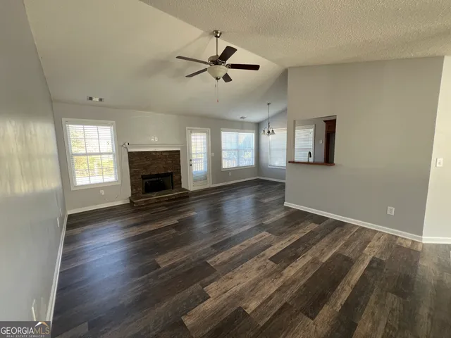 an empty room with wooden floor fireplace and windows
