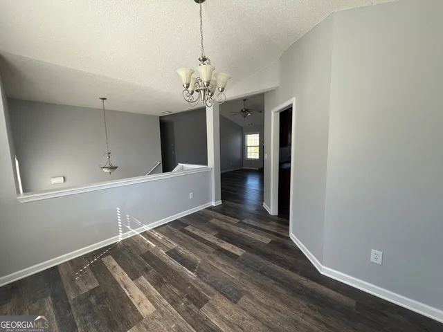 a view of a room with a chandelier and wooden floor
