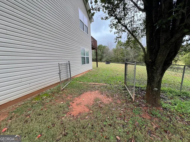 a view of a yard with plants and a large tree