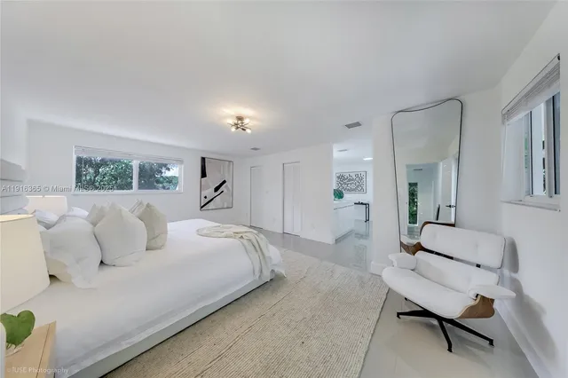 a spacious bedroom with a bed a couch and a view of en suite bathroom