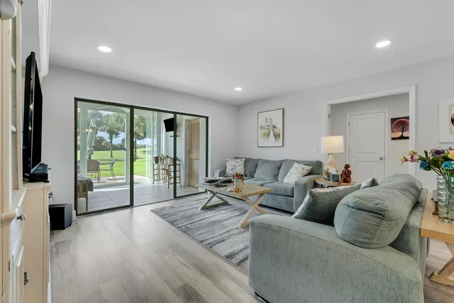 a living room with furniture large window and wooden floor