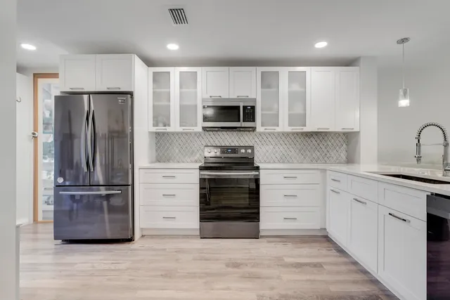 a kitchen with stainless steel appliances a stove a sink and a refrigerator