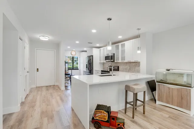 a kitchen with stainless steel appliances granite countertop a sink a stove a refrigerator and island with wooden floor