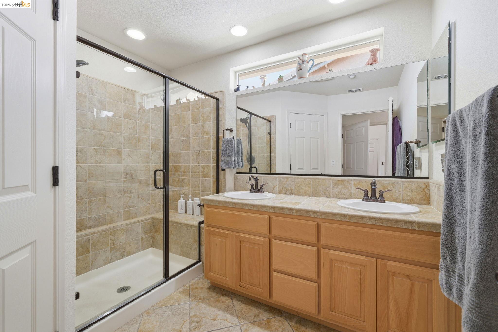 1024 Diamante Rio Vista, CA 94571 - Photo 20 of 27 Bathroom featuring a dual vanity with light wood cabinetry, a glass-enclosed shower with tiled walls and an integrated bench, and recessed ceiling lighting
