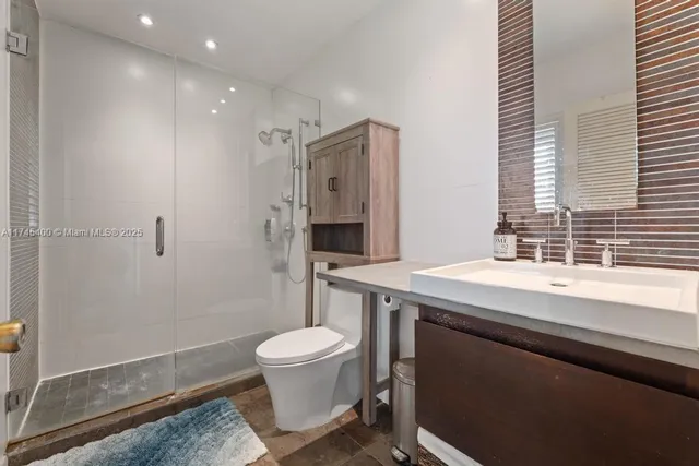 a bathroom with a sink a toilet a mirror and shower