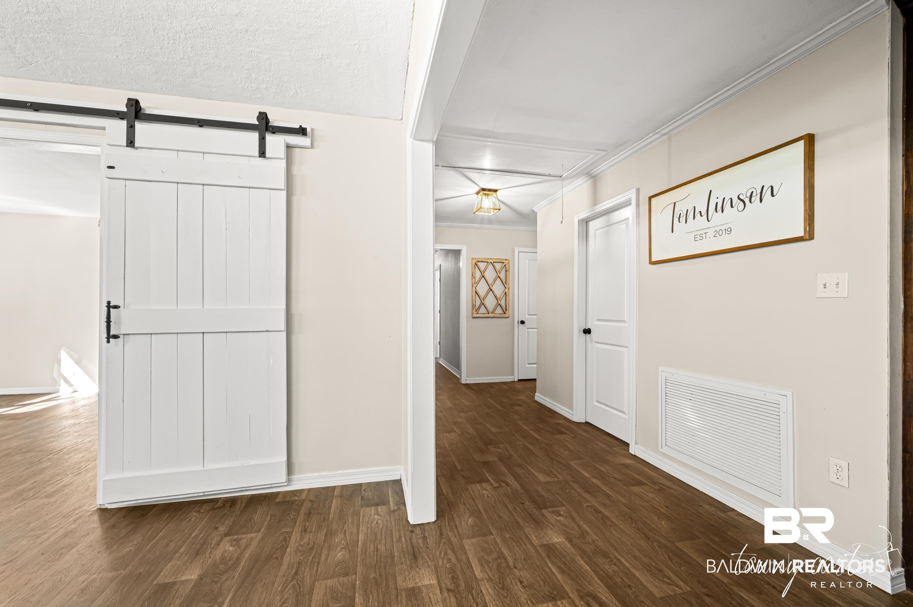 3086 Wild Fork Road Frisco City, AL 36445 - Photo 4 of 30 Hallway featuring dark wood-style flooring, a barn door, and crown molding