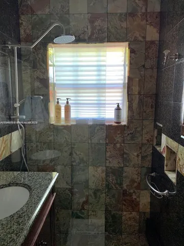 a bathroom with a granite countertop sink a mirror and a shower