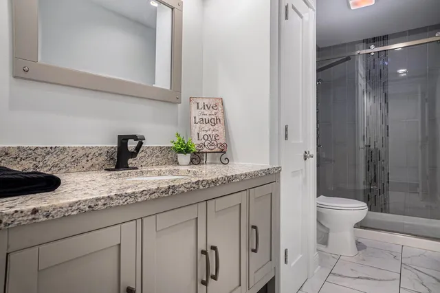 a bathroom with a granite countertop sink toilet and shower