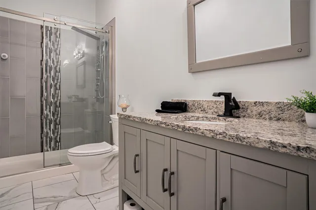 a bathroom with a granite countertop sink toilet and shower