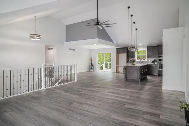 a view of a kitchen with wooden floor a sink a refrigerator and window