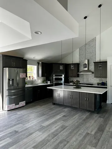 a large kitchen with kitchen island a counter top a stove a sink and a refrigerator