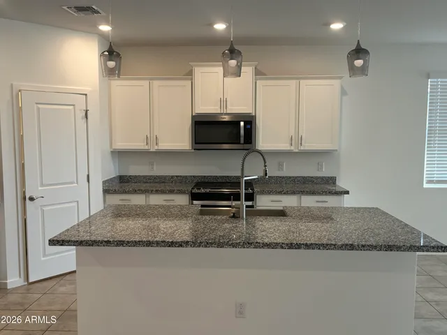 a kitchen with kitchen island granite countertop a sink a counter top space and cabinets