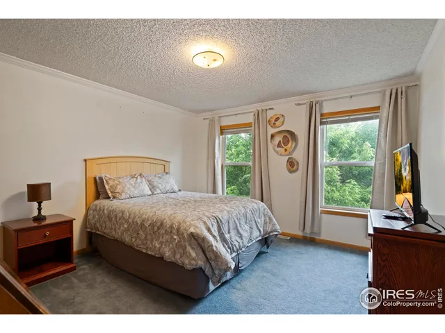 a bedroom with a bed and a flat tv screen on dresser