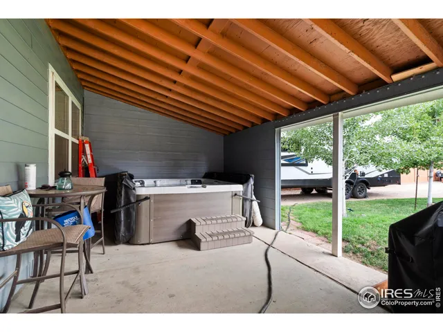 a view of a backyard with table and chairs under an umbrella with a barbeque