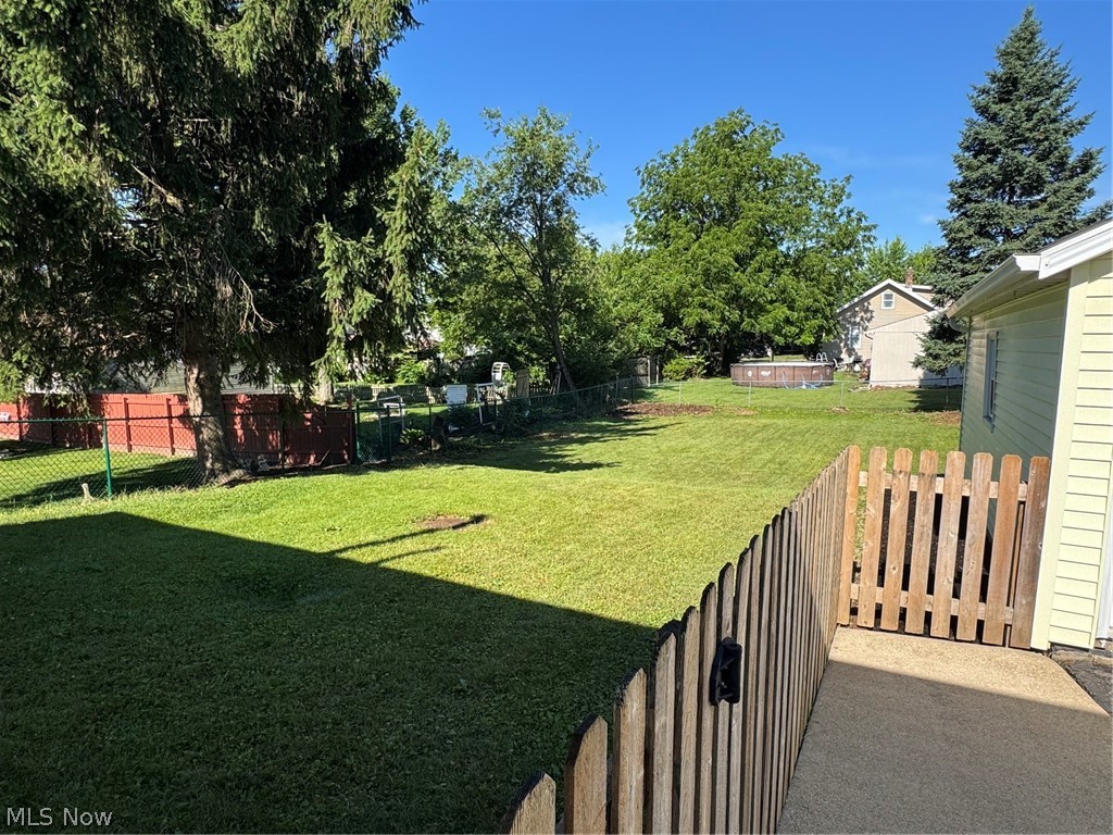 145 Anna Avenue Northwest Canton, OH 44708 - Photo 25 of 27 Expansive backyard featuring a large grassy area, mature trees, a wood picket fence, and chain-link fencing