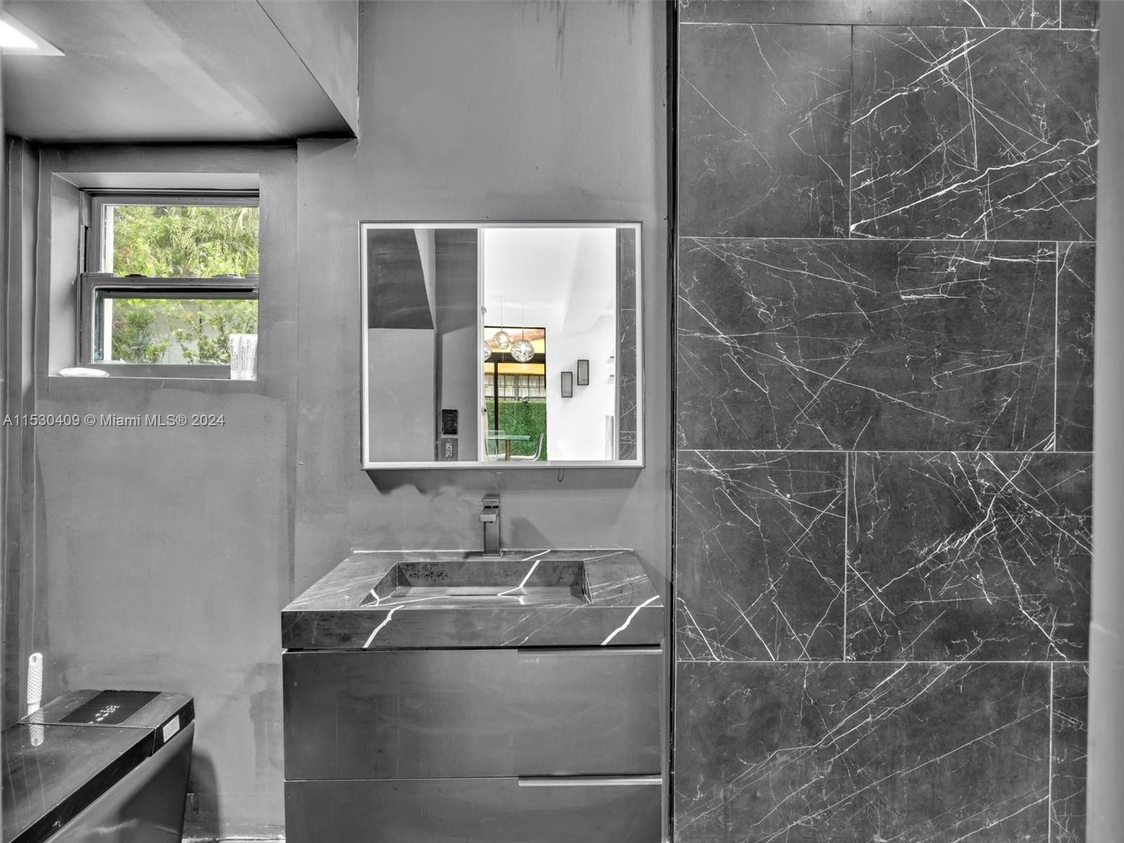 3010 Alton Road Miami Beach, FL 33140 - Photo 23 of 41 a bathroom with a granite countertop sink a toilet and a mirror