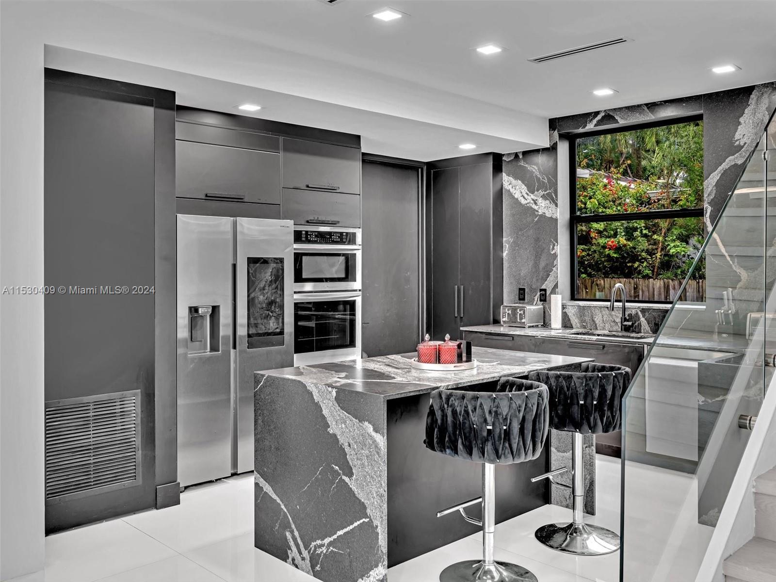 3010 Alton Road Miami Beach, FL 33140 - Photo 10 of 41 a kitchen with stainless steel appliances kitchen island granite countertop a refrigerator a stove a sink dishwasher with a dining table and chairs