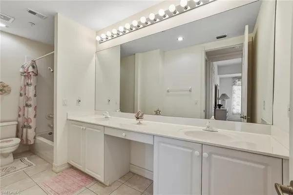 a bathroom with a double vanity sink mirror and toilet