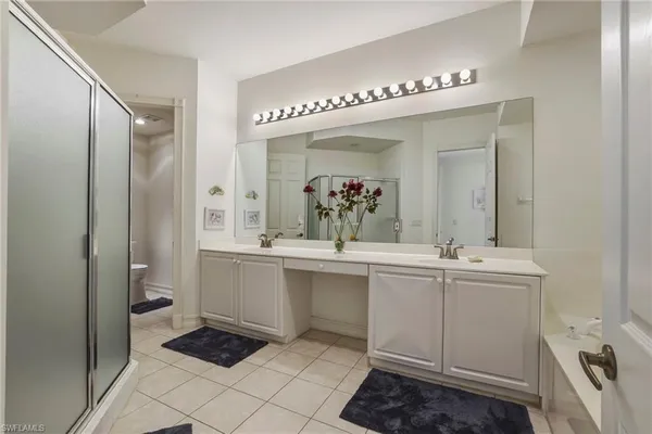 a spacious bathroom with a double vanity sink a toilet and a mirror