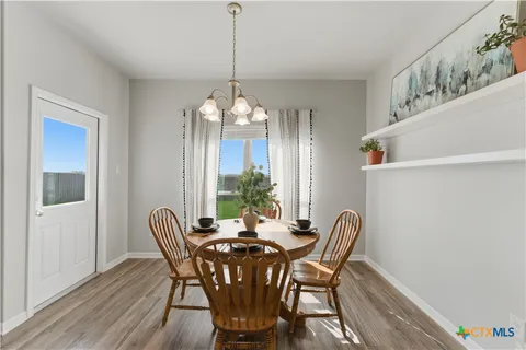 a view of a dining room with furniture a chandelier and wooden floor